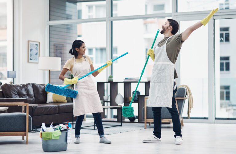 Shot of a happy young couple having fun while mopping the floor at home.